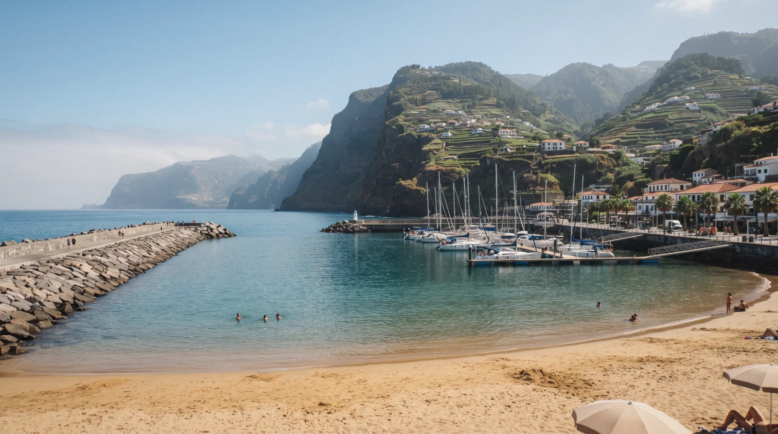 The imported golden sand of Praia da Calheta and its breakwaters in Calheta, Madeira, Portugal