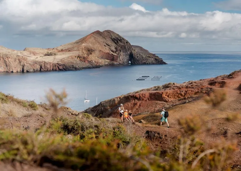 A narrow ridge trail cutting through red volcanic cliffs at Ponta de São Lourenço on a PR8 hike transfer in Ponta de Sao Lourenco, Madeira