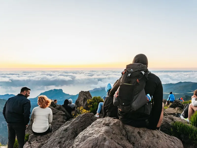 Hikers silhouetted on the PR1 ridge trail above the clouds near Pico do Arieiro on a Madeira sunrise hiking transfer in Pico do Arieiro, Madeira